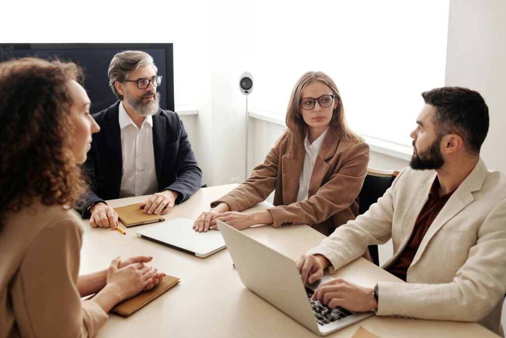 Home Business colleagues engaged in a serious discussion around a conference table.