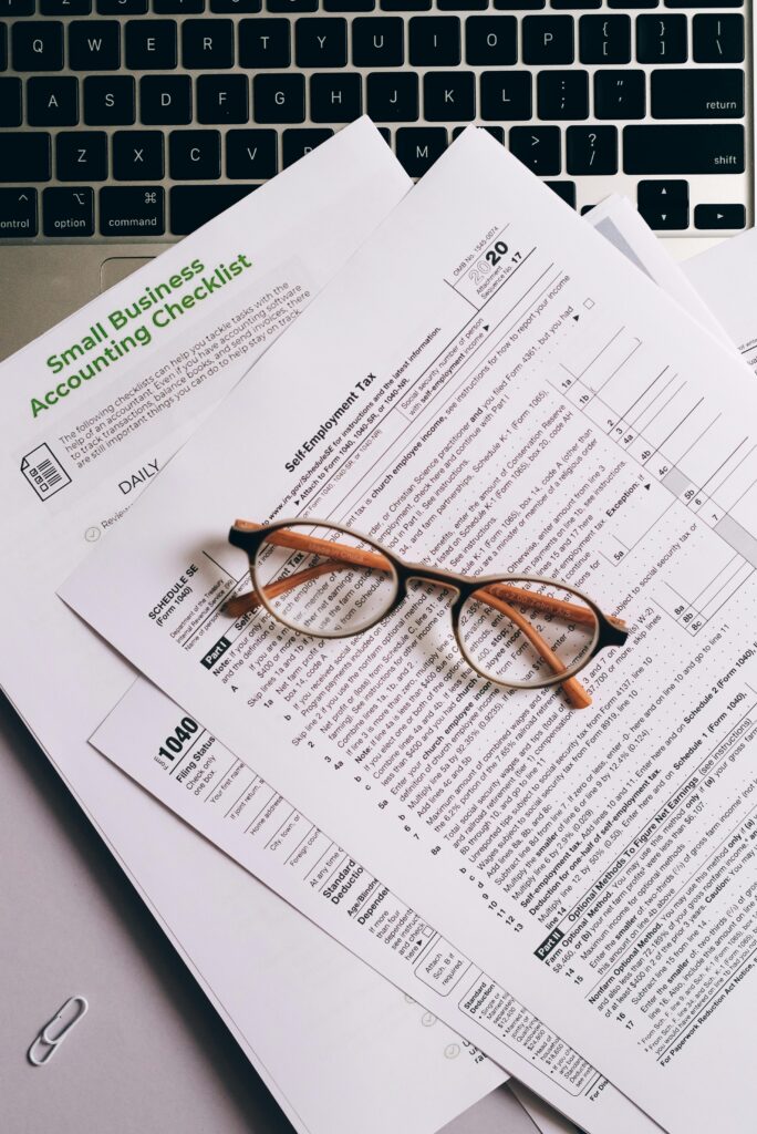 Home Overhead view of tax documents and eyeglasses on a laptop keyboard, ideal for finance or accounting themes.